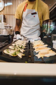 A street food vendor is cooking taiyaki, a popular Japanese fish-shaped snack, on a hot plate.