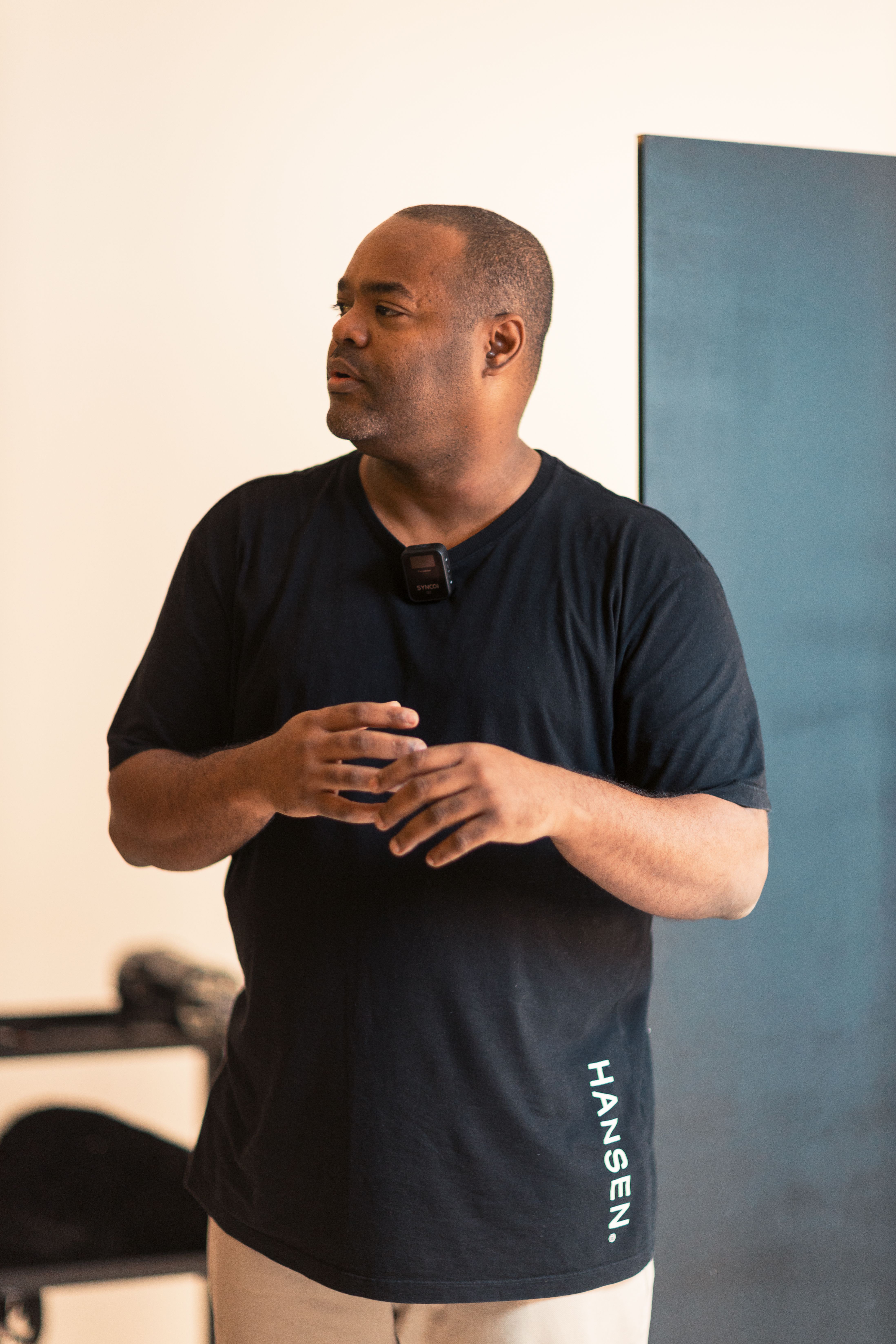 A thoughtful man standing indoors wearing a black t-shirt. Perfect for lifestyle or business contexts.