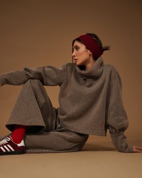 Woman in beige outfit sitting on a neutral background, exuding style and comfort. — photo by sara kazemi