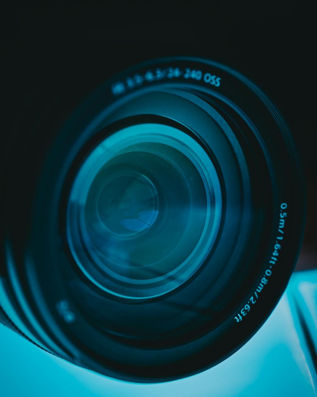 Close-up shot of a camera lens showcasing intricate design and blue tones.