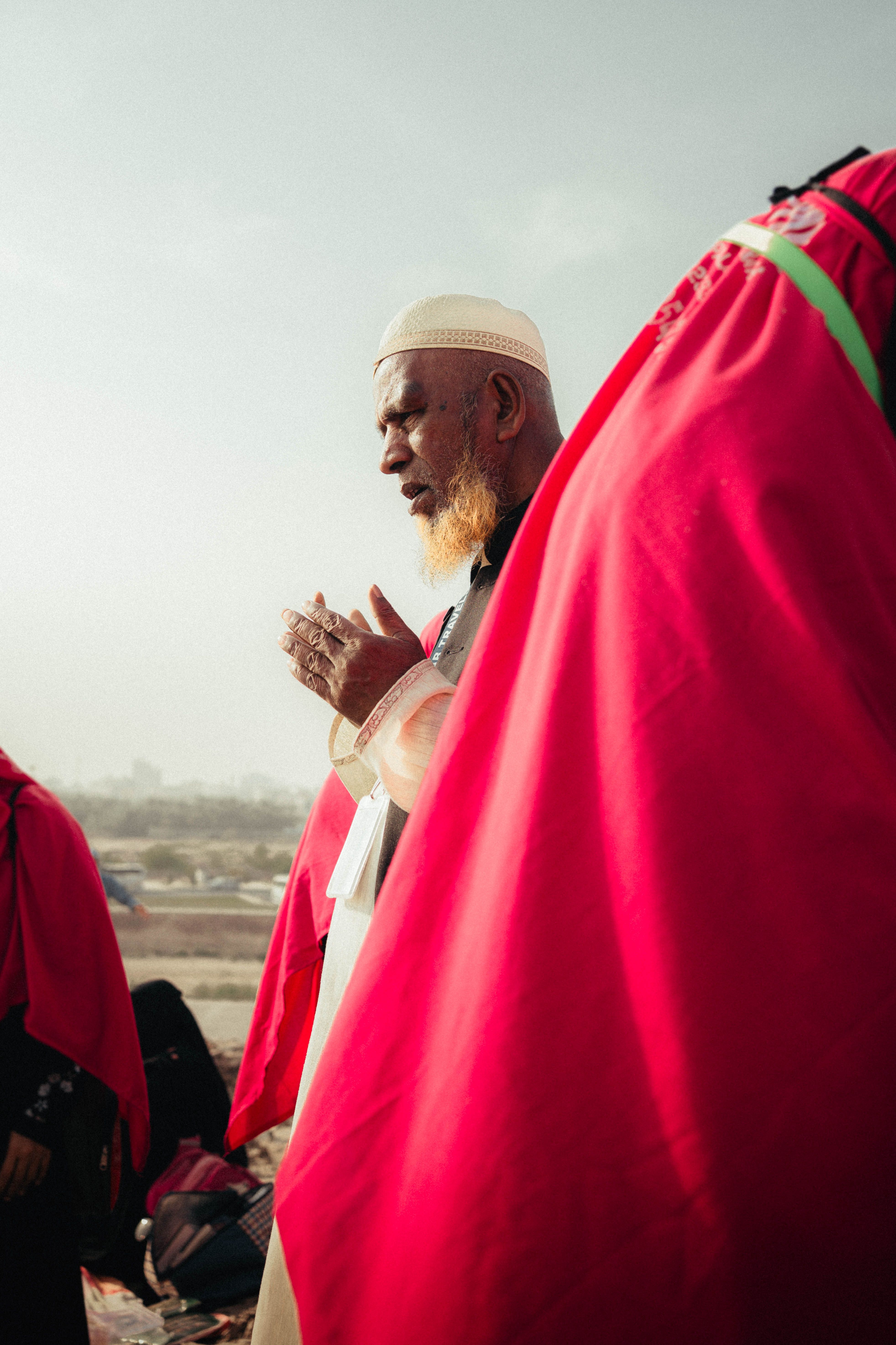 Elderly Man Praying Outdoors in Traditional Attire · Free Stock Photo