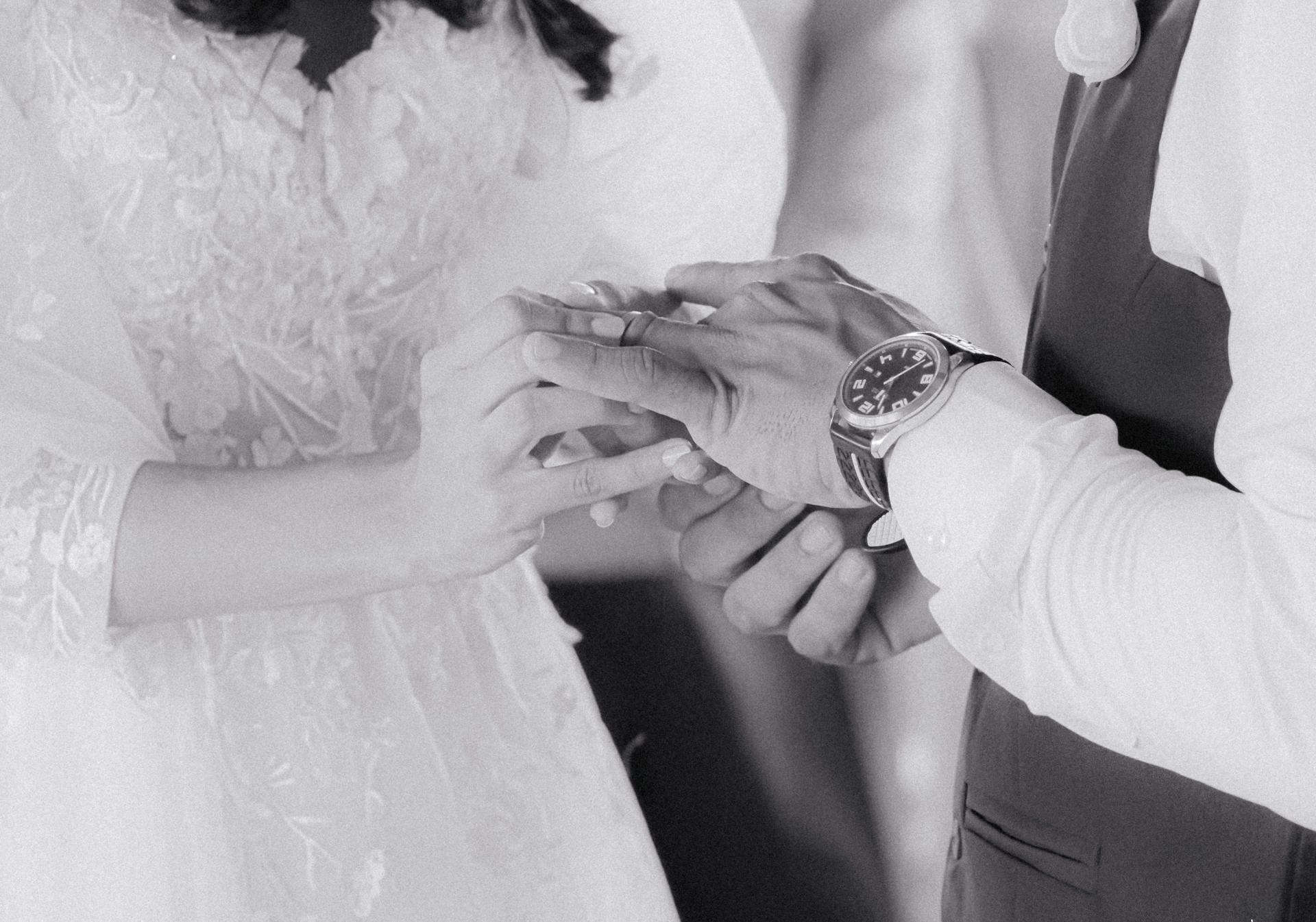 A couple exchanging rings during a wedding ceremony in a romantic black and white tone.