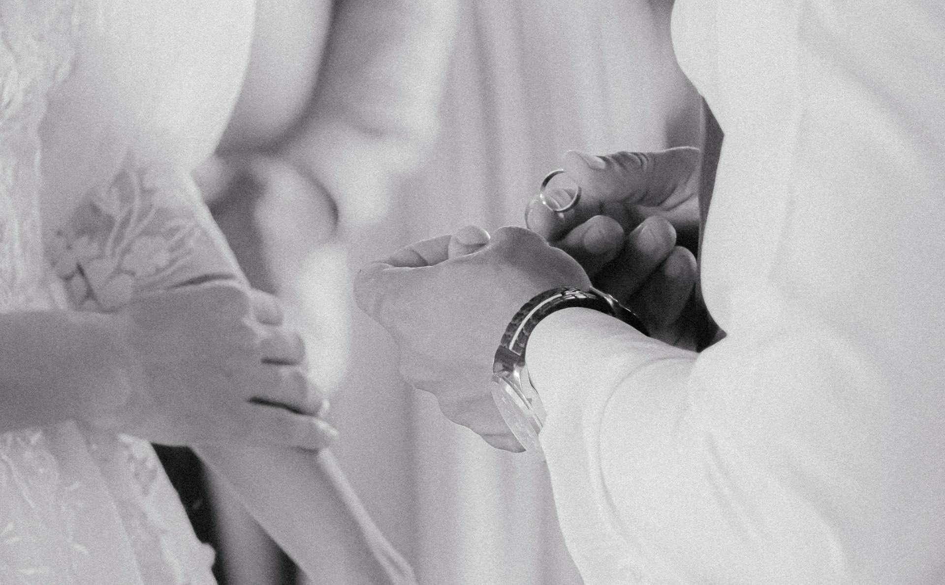 Close-up black and white photo capturing an intimate ring exchange at a wedding ceremony.