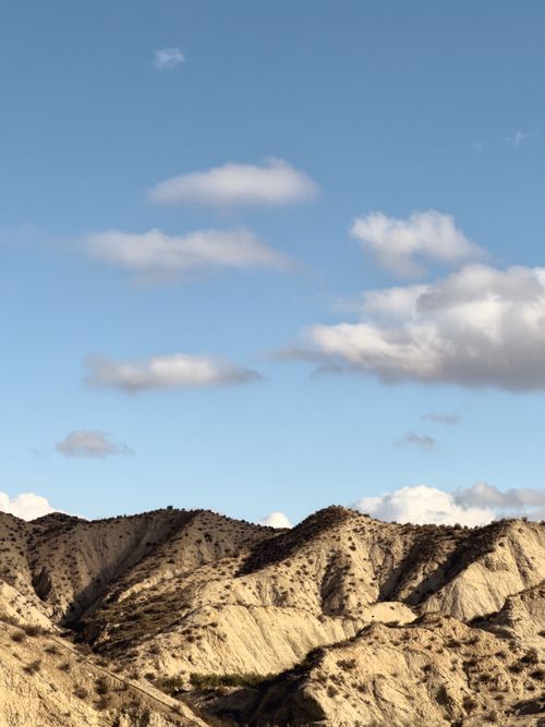 Free Expansive desert hills under a blue sky with scattered clouds. Stock Photo