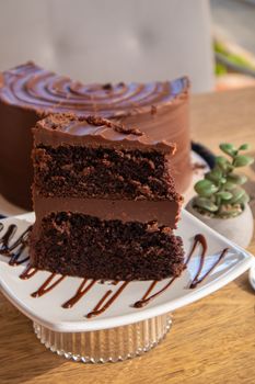 Close-up of a decadent chocolate layer cake slice with frosting on a plate, perfect for dessert lovers.