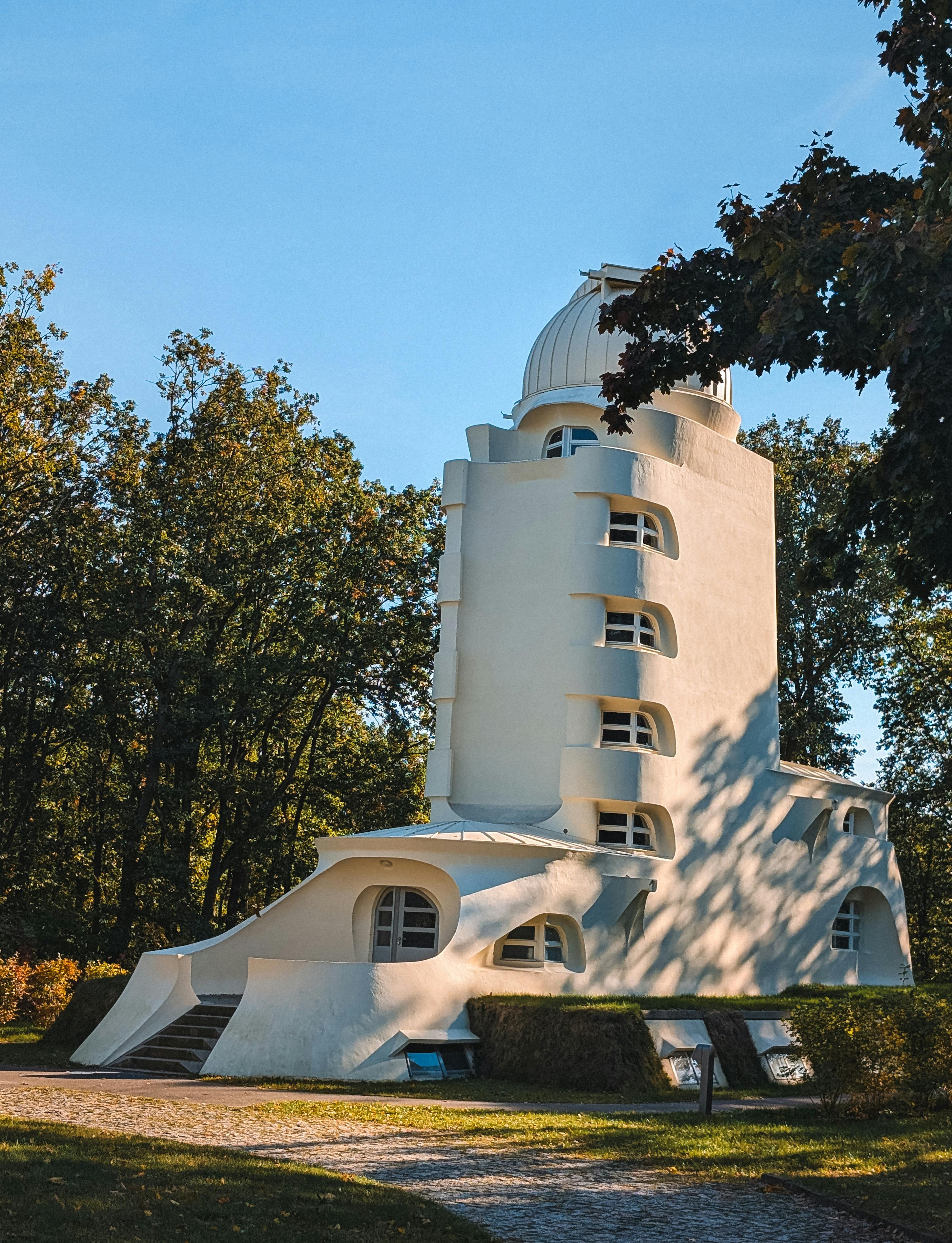 The Einstein Tower surrounded by lush trees under a clear blue sky, showcasing its unique architecture.