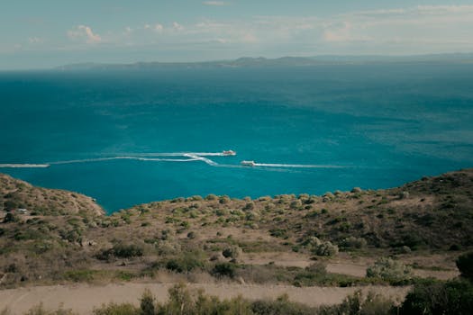 A breathtaking aerial perspective of the Mediterranean Sea with boats leaving trails on the water.
