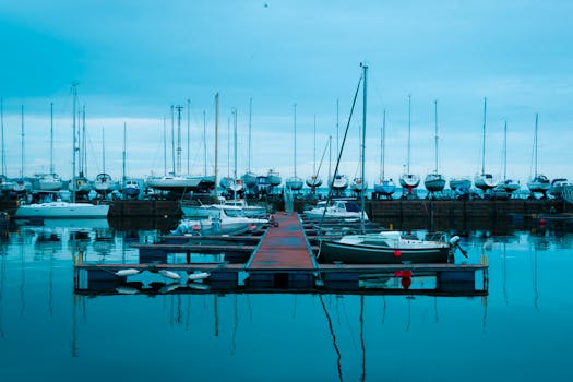A serene view of a marina in Scotland with boats docked at the pier under a blue sky.