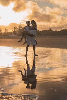 日落时分，一对夫妇在海滩上拥抱的剪影倒映在水中