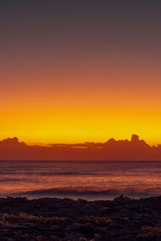 Stunning golden sunrise over Akumal Beach, Quintana Roo. Vibrant orange sky reflecting on tranquil ocean waves.