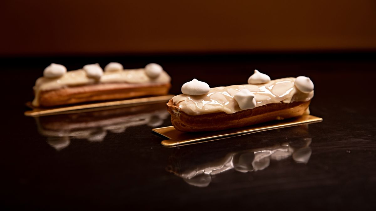 Two éclairs standing on a mirrored surface that doubles them.