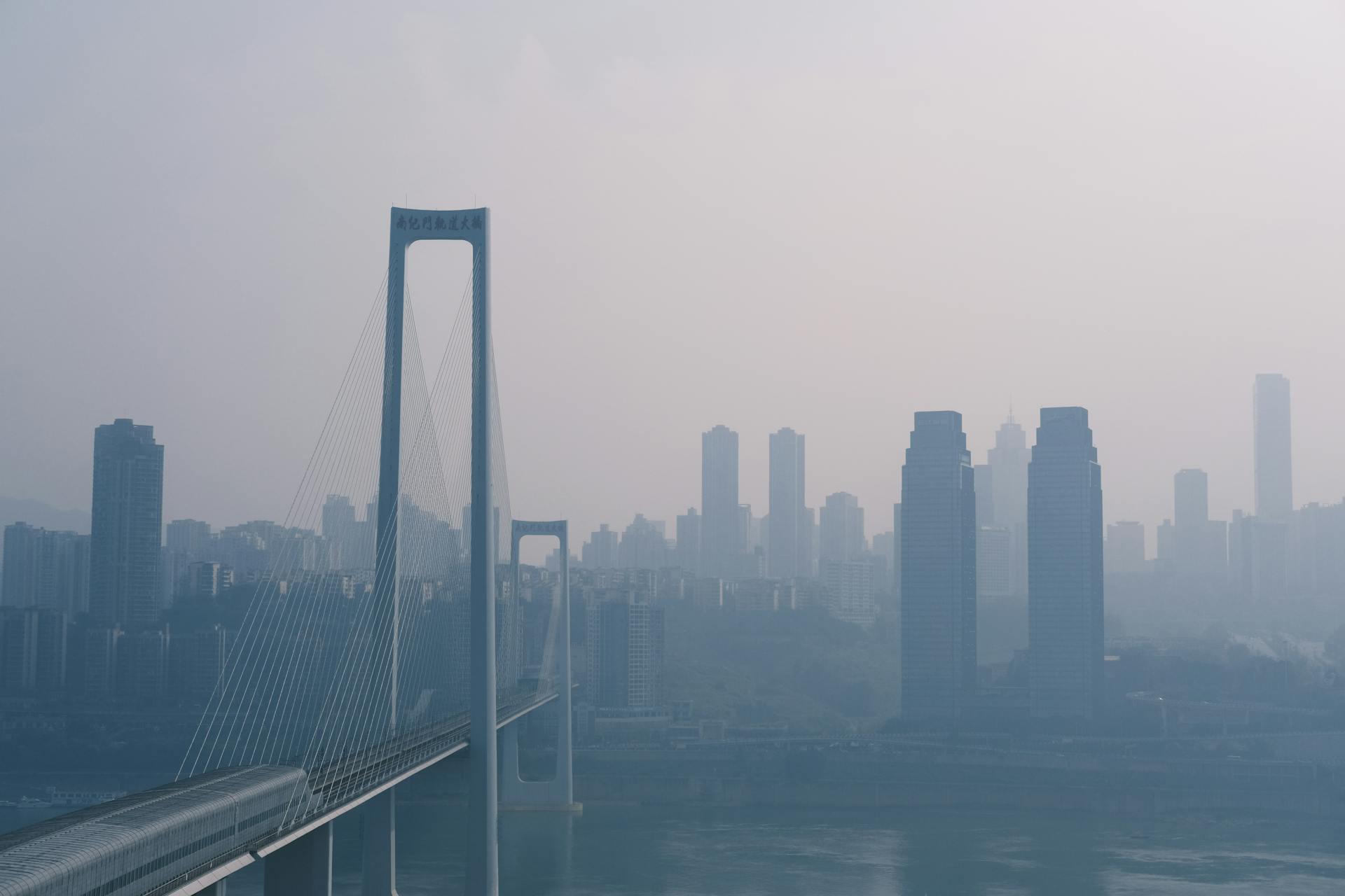 A foggy city skyline with a prominent bridge dominating the scene.