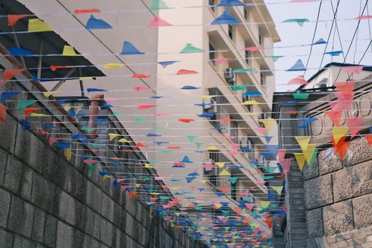 Vibrant multicolor flags decorate an urban alley, creating a festive atmosphere.