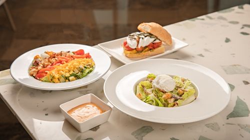 Free A vibrant salad, sandwich, and dipping sauce beautifully arranged on a table in an indoor setting. Stock Photo