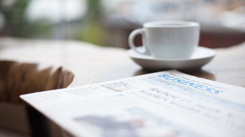 Close-up of a coffee cup and business newspaper on a table, perfect for office or breakfast themes.