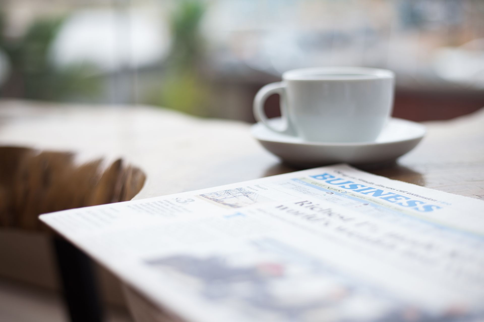 Close-up of a coffee cup and business newspaper on a table, perfect for office or breakfast themes.