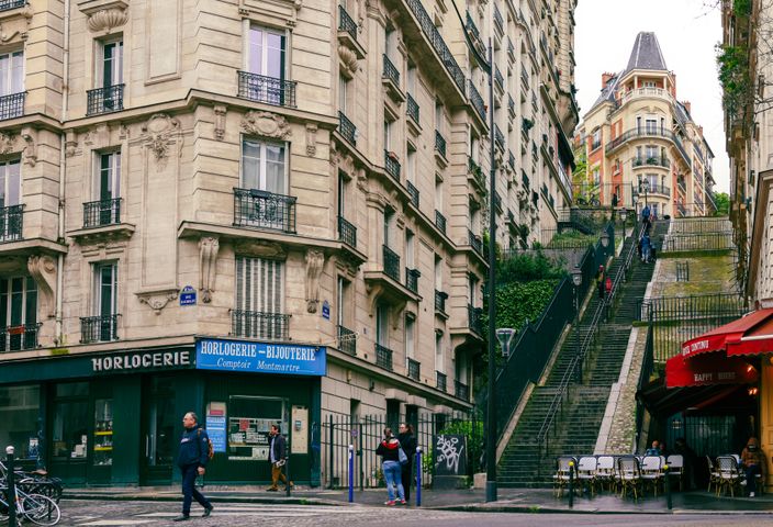 Discover a quaint Parisian street in Montmartre, showcasing elegant architecture and lively city life.