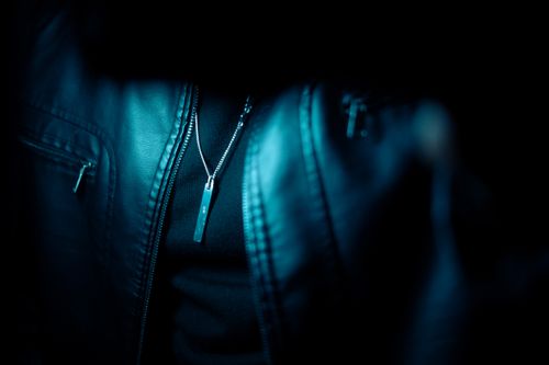 Free Detailed view of a leather jacket with a pendant in a dark, moody setting. Stock Photo
