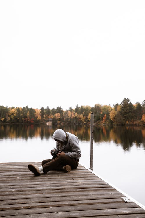 Person Sitting on Wooden Dock