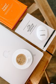 Elegant flat lay of a workspace with coffee, journals, and laptop on a wooden table.