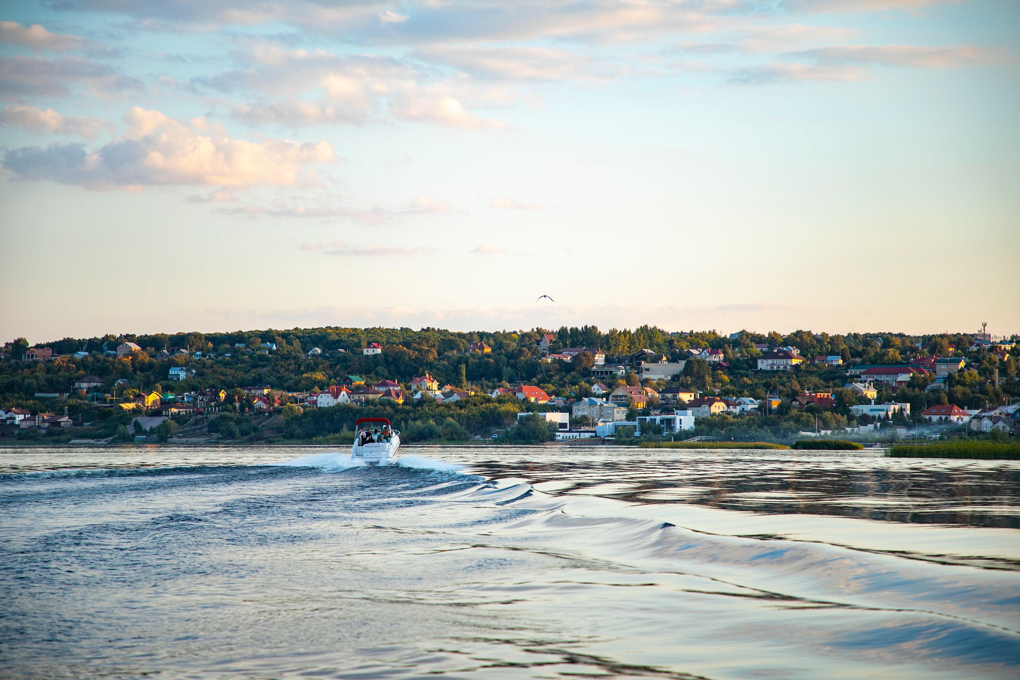 A scenic view of a river and motorboat with a vibrant town backdrop during sunset in Russia.