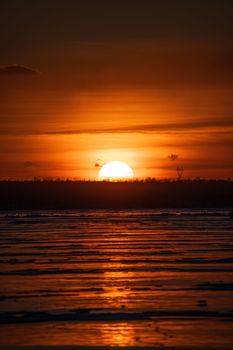 Golden sunset reflecting over rippling ocean waters, creating a dramatic and peaceful scene.