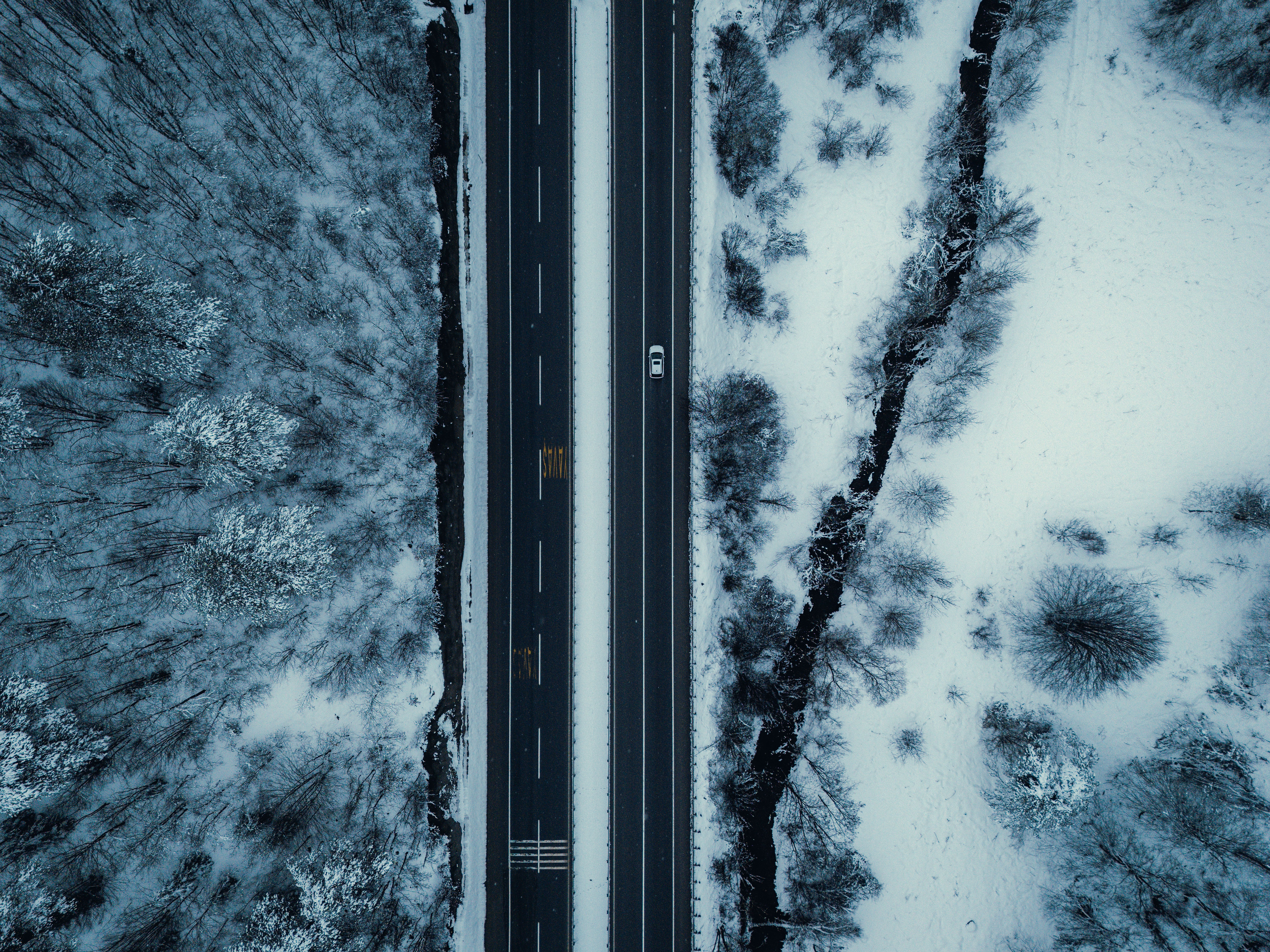 Aerial View of Snowy Road Through Winter Forest · Free Stock Photo