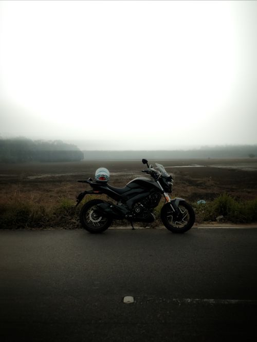 Free A motorcycle parked on a road in Kollam, Kerala, India with foggy fields in the background. Stock Photo