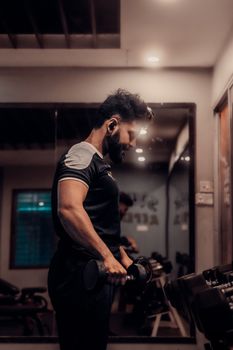 Focused man lifting dumbbells in a gym in Comilla, Bangladesh, embodying personal fitness goals.