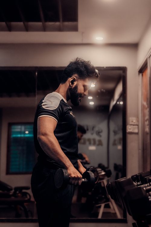 Free Focused man lifting dumbbells in a gym in Comilla, Bangladesh, embodying personal fitness goals. Stock Photo