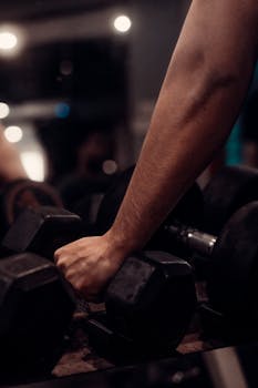 Close-up of a person's hand gripping a dumbbell reflecting intense workout motivation.
