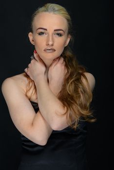 Portrait of a young woman with striking makeup and styled hair against a black background. Fashion and elegance captured.