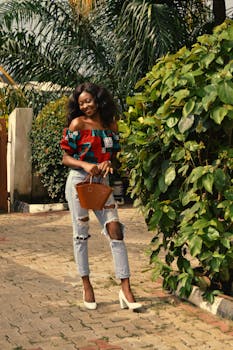 在阳光明媚、绿树成荫的户外，时尚的非洲女性微笑着摆出姿势