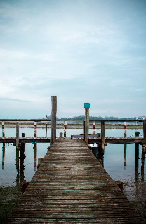 Free Tranquil scene of a wooden pier extending into the calm waters of Grado Lagoon, Italy. Stock Photo