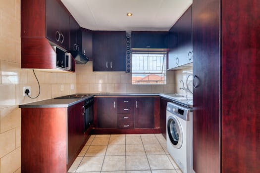 Spacious modern kitchen with cherry wood cabinets and stainless steel appliances.