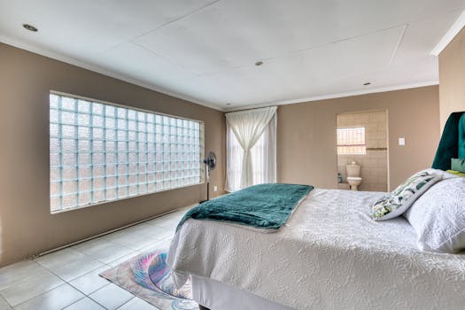 Bright and airy modern bedroom with large glass block window and elegant decor.