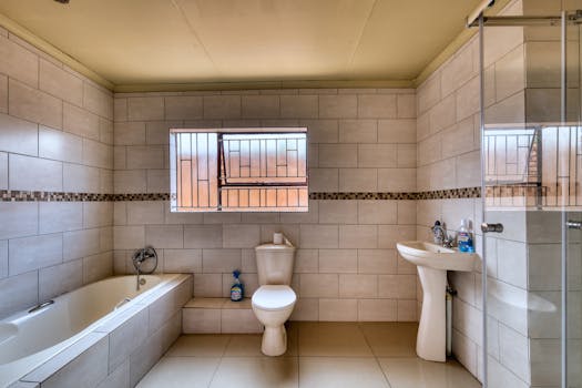 Spacious bathroom featuring neutral tiles, bathtub, and modern fixtures. Ideal for home improvement and real estate listings.