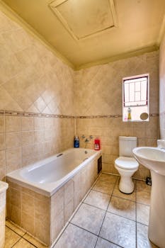 Bright bathroom with tiled walls, bathtub, and white fixtures, perfect for home interior inspiration.