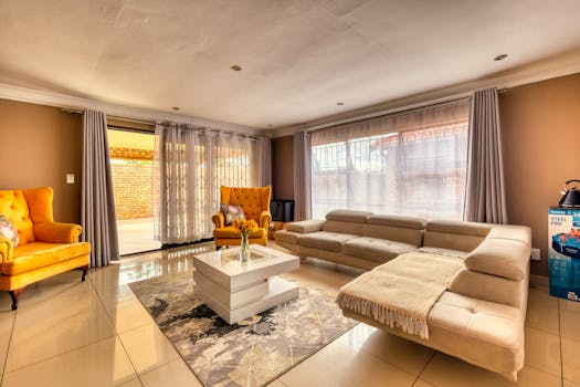 Cozy modern living room with vibrant chairs, neutral sofa, and natural light.