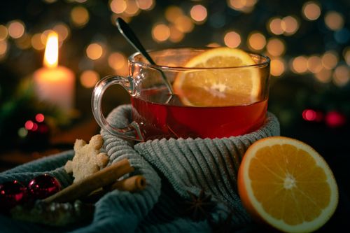 Free Warm cup of tea with oranges and cinnamon sticks, evoking winter magic beside candlelight. Stock Photo