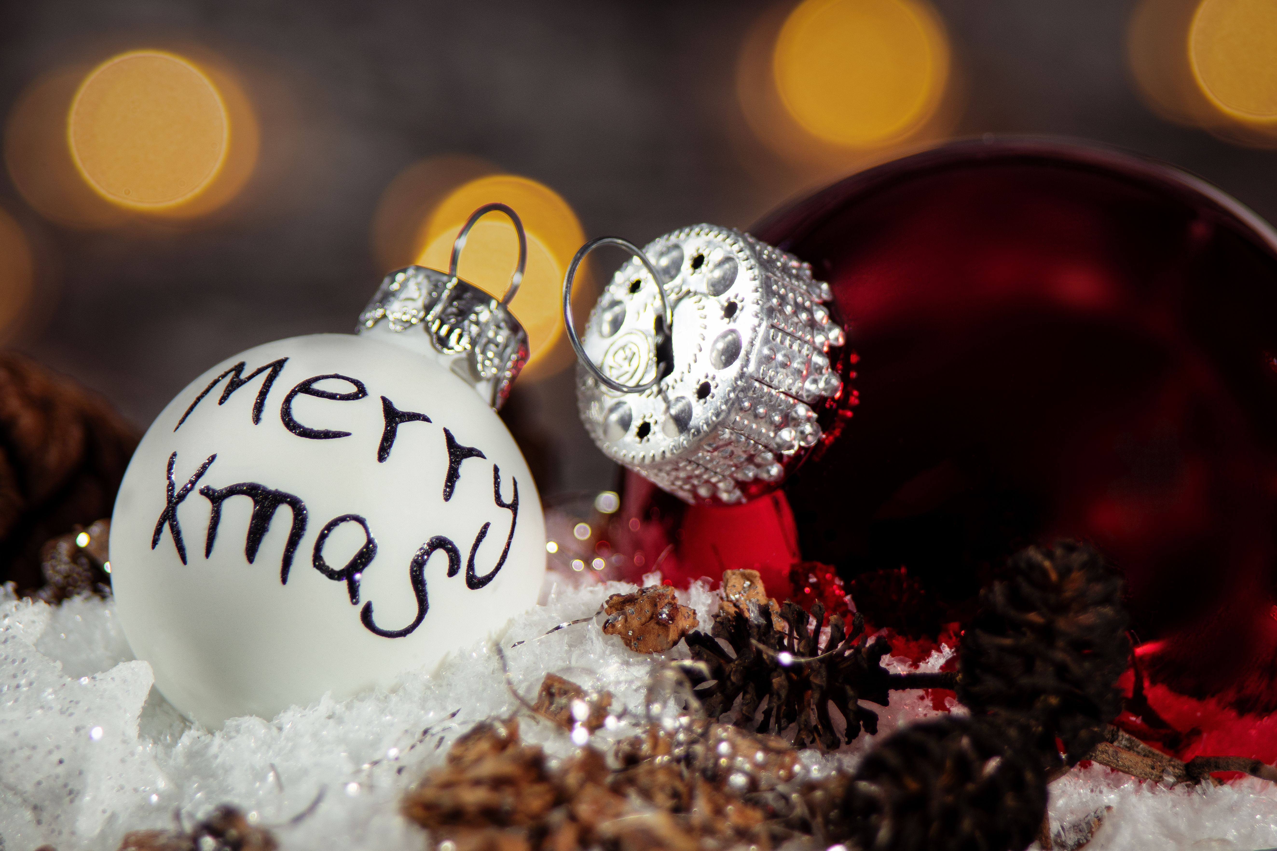 Colorful Christmas ornaments with pine cones on a snowy background, capturing holiday spirit.