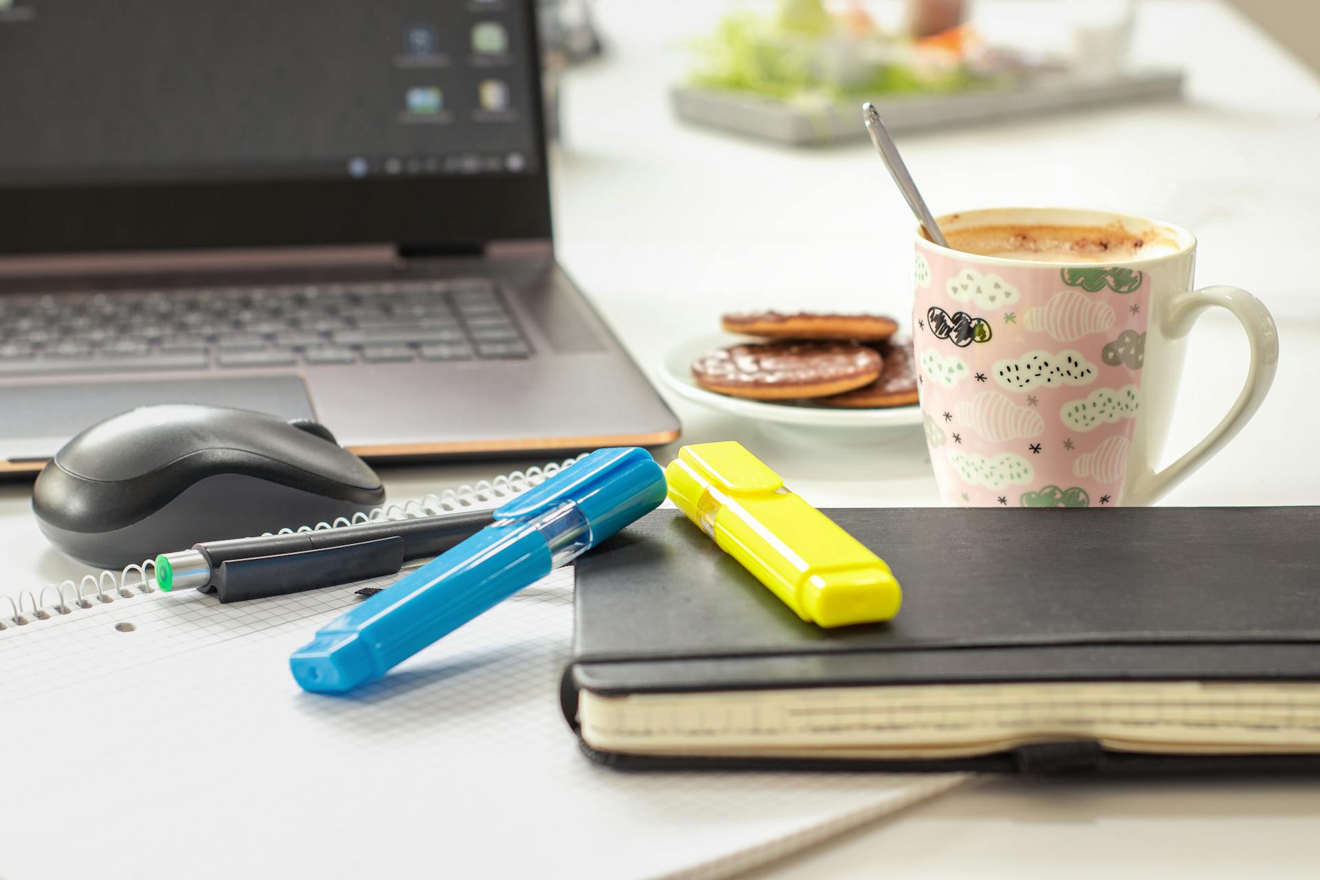 A bright and inviting workspace featuring a laptop, stationery, and a mug of coffee, perfect for productivity.