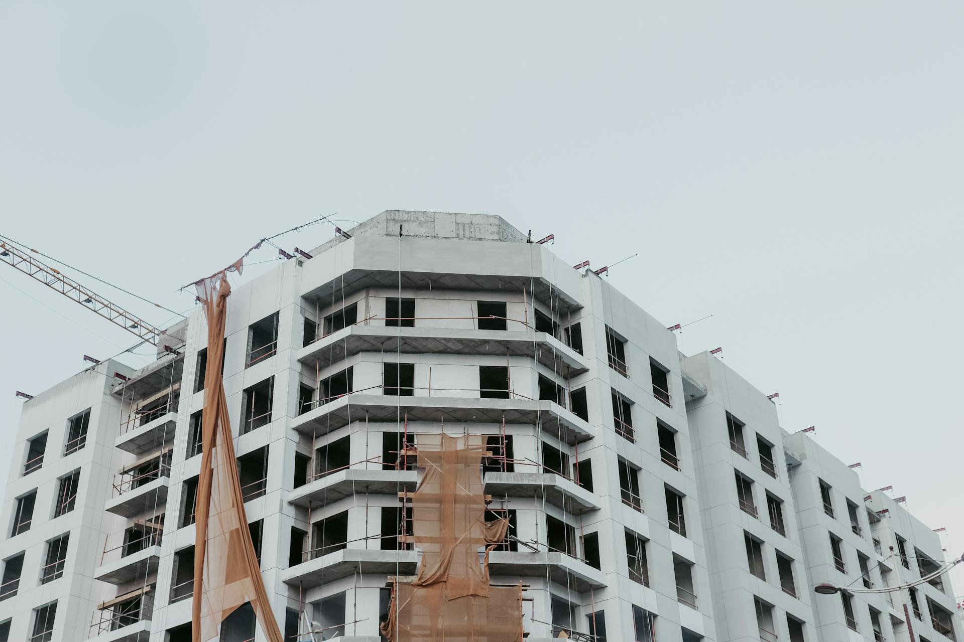 A modern high-rise building under construction featuring scaffolding and cranes against a clear sky.