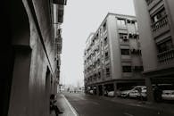 这是一张城市街道的黑白照片，照片里有公寓楼和停放的汽车