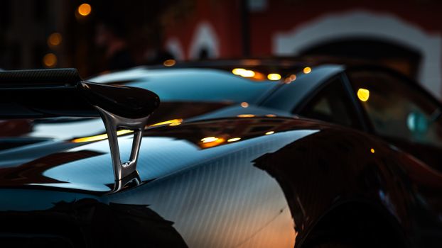 Close-up of a hypercar with carbon fiber details and elegant reflections at dusk.