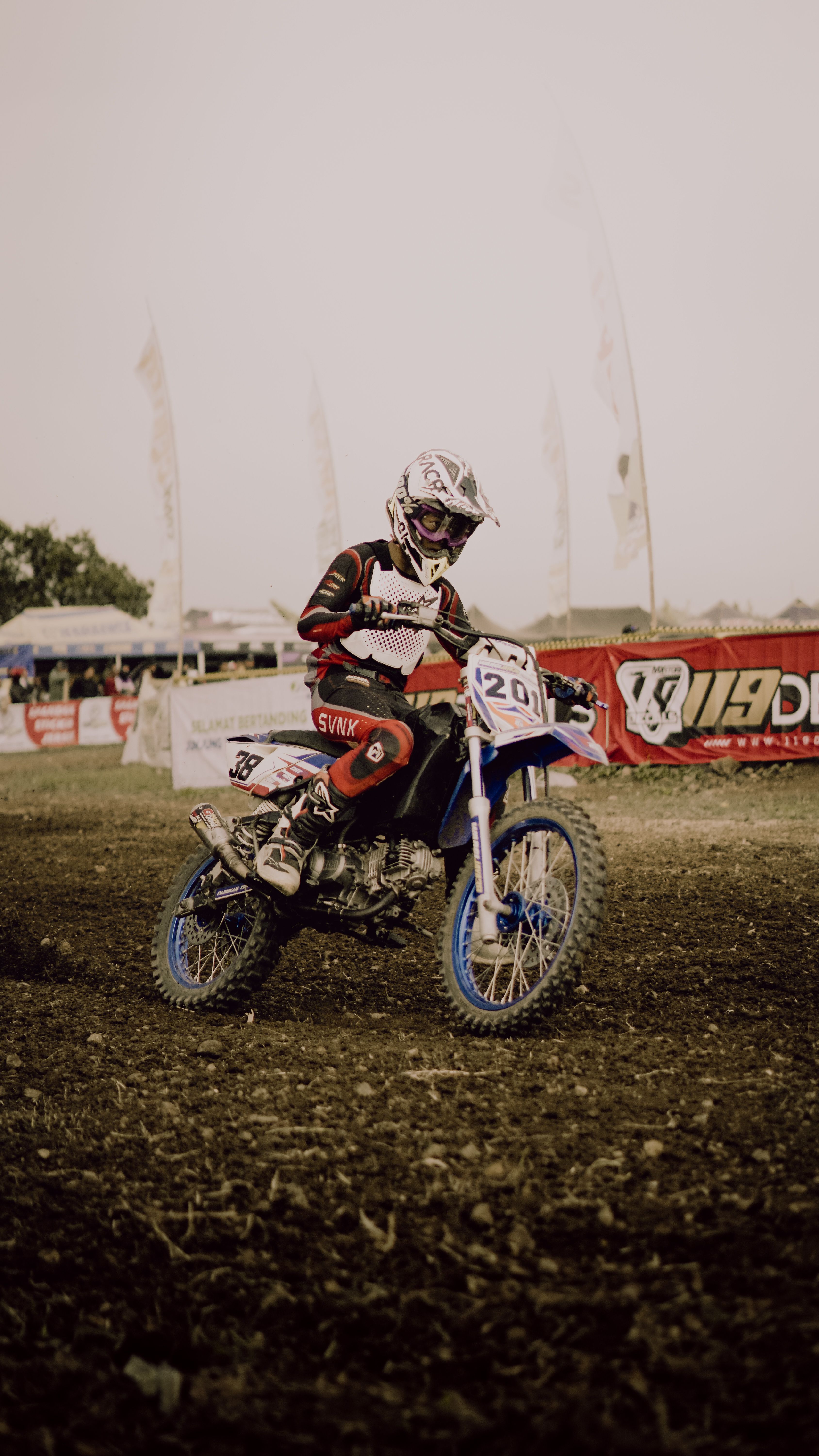 Exciting motocross action on a dirt track in Indonesia, showcasing skill and speed.