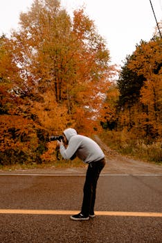 一名男摄影师在森林地区拍摄秋叶，画面充满活力