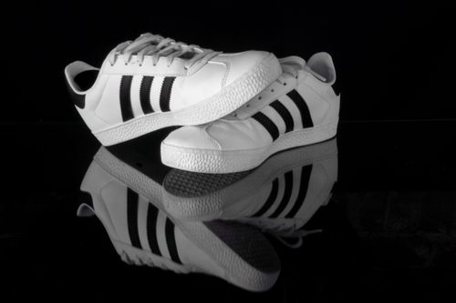 Free Stylish black and white sports shoes displayed on a reflective surface, emphasizing sleek design. Stock Photo