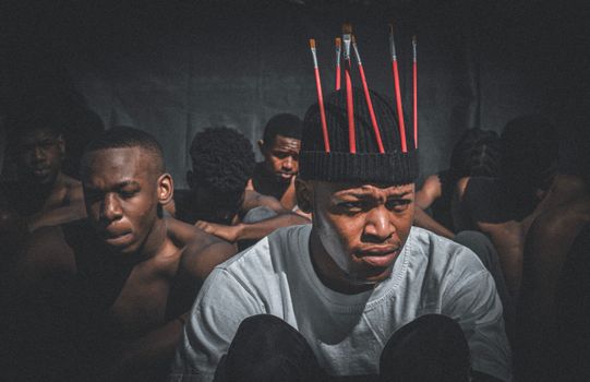 Artistic group portrait with brushes in hats, conveying creativity and intensity.