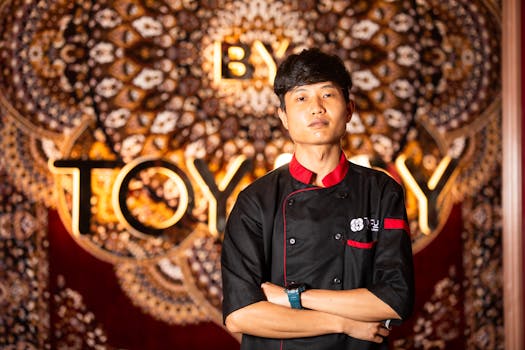 Professional chef posing confidently in a beautifully decorated restaurant interior with intricate designs.